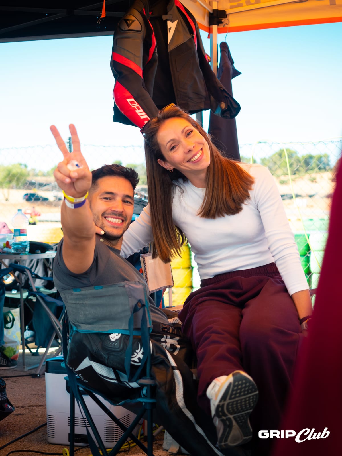 Una pareja saluda sonriente desde la carpa de su equipo